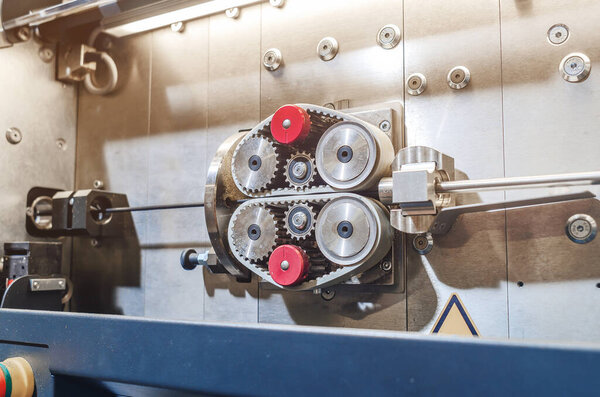 Pulling wire through gears on machine. Part of industrial equipment at modern plant.