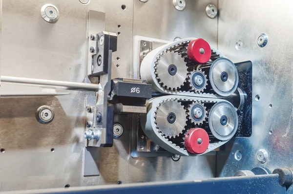 Pulling wire through gears on machine. Part of industrial equipment at modern plant.  Side view