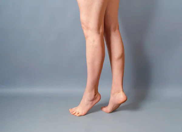 Gri Arka Planda Kadın Uzun Çıplak Bacaklar Ayaklar Parmak Uçlarında — Stok fotoğraf