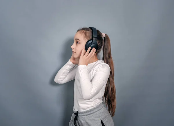 Side View Little Girl Headphones White Shirt Gray Sweatpants Holds — Stockfoto