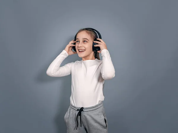 Energetic Little Girl Headphones White Shirt Gray Sweatpants Holds Headphones — Stockfoto