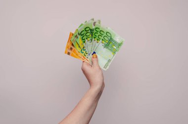 Woman holds euro cash in hand on light background