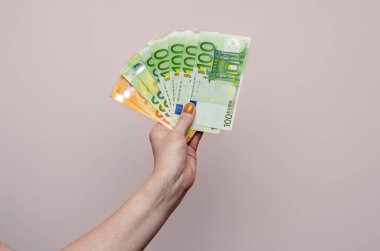 Woman holds euro cash in hand on light background