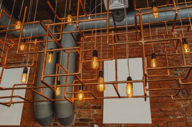 Kafedeki bakır borulardan yapılmış modern tavan lambası.