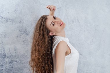 Portrait of charming young woman. Long curly dark hair. She threw her head back. Dazzling smile. White blouse