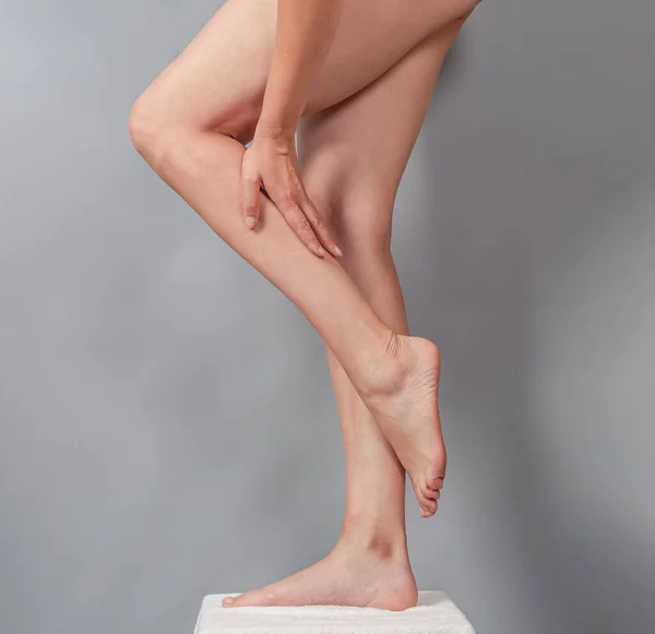 Naked female long legs. The hand massages leg. Smooth skin on legs after depilation.