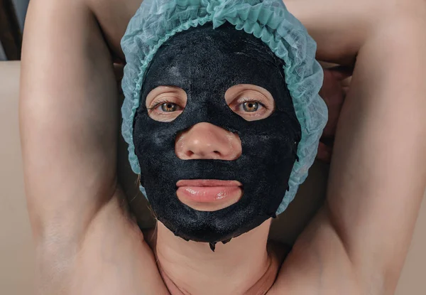 Rejuvenating procedures for face. Black fabric mask on woman\'s face.