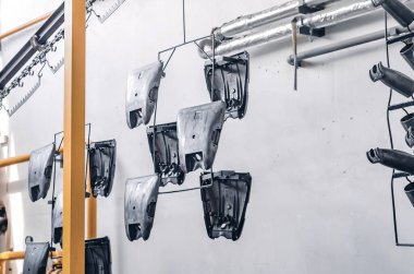 Production details hung on metal hangers in workshop. Strong, rough, industrial tools. Industrial background.