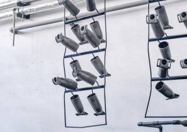 Production details hung on metal hangers in workshop. Strong, rough, industrial tools. Industrial background.