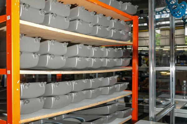 Shelves with gray plastic containers in production. Storage. Industrial background