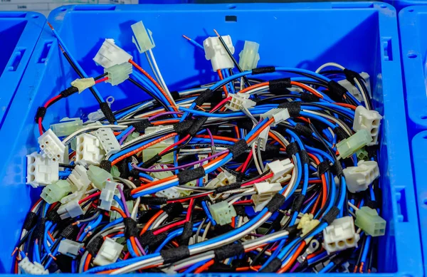 Blue container with bunch of colored cables, connections, wires. Industrial background.