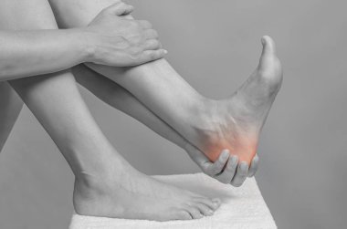 Female hands holding foot. Pain in  heel. Female feet on white towel. Heel massage.