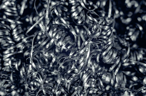 Iron metal shavings, curls, gray metal background. Macro shooting of metal processing, turning business.