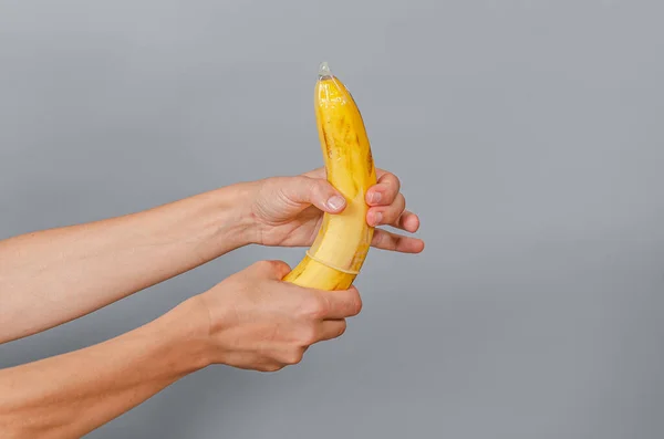손으로 콘돔을 바나나 얹는다 바나나와 콘돔을 여자들 보호받는 — 스톡 사진