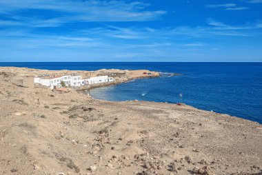 Binalarla deniz kıyısına bakıyorum. Denizde körfez. Kum.