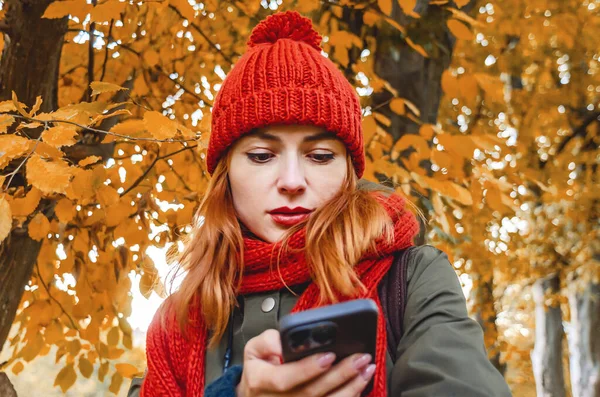 Стильная Девушка Мобильным Телефоном Осеннем Парке Оранжевая Вязаная Шляпа Шарф — стоковое фото