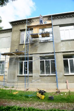 Ön cephe yenileme ve yenileme. İnşaat işleriyle uğraşan bir müteahhit evin dış duvarını boyamadan önce sıva ile kaplıyor.. 