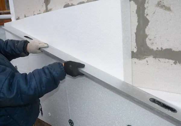 外墙泡沫板绝缘 一个建筑承包商正在将硬质聚苯乙烯和泡沫隔热材料安装到房屋墙壁上 并在使用一种精神水平 — 图库照片
