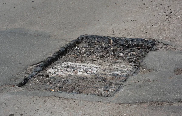 Yol inşaatı veya garaj yolu tamiri: çukurun temizlenmesi ve yeniden şekillendirilmesi yoluyla asfalt yolu tamir etmek.  