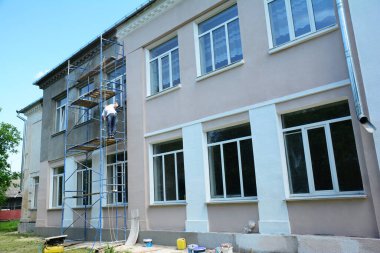 Renklendirme, yenileme, sıva yapma ve sıva maskesini boyama. Müteahhitler bir evin dış duvarını kaplamak için sıva uyguluyorlar..