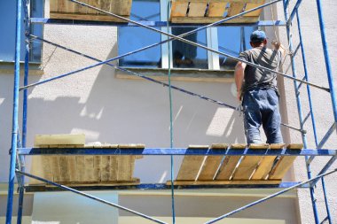 Bir evin dış duvarında sıva şeklinde bir resim. İnşaat işleriyle uğraşan bir müteahhit boyacılık yapıyor, dış cepheyi yeniliyor..