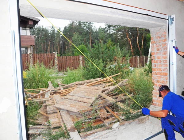 A new garage door installation, repair. An installer is measuring a garage door frame before a roll up door installation.