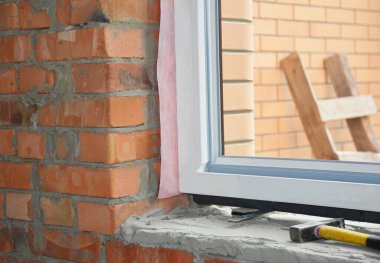 Pencere kurulumu. Yeni inşa edilmiş bir tuğla eve upvc plastik pencere çerçevesi ekleniyor.