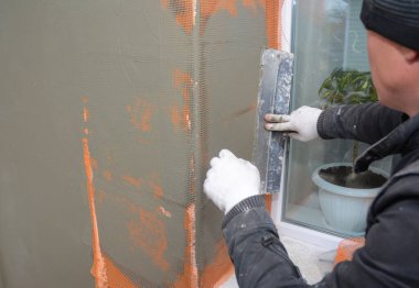 Müteahhit pencere kenarlarını macun bıçağıyla sıva, fiberglas örgü, katı yalıtım üstüne alçı örgüsü ile kaplıyor.. 