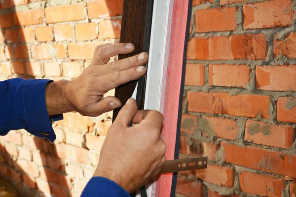 Contractor glue waterproofing and insulation tape on new house window installation. Close up on window installation.