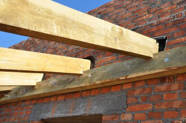 Wooden beams frame roofing construction on brick house  wall.