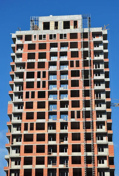 High-level brick wall building with wall construction and windows installation.