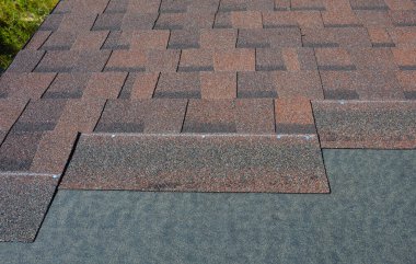 Laying asphalt shingles with vapor barrier on the house roof. Asphalt shingles installation on the rooftop.  Close up on Asphalt shingles texture background.