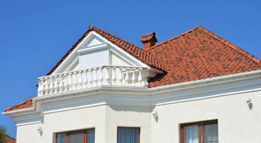 Beyaz duvarlı modern lüks bir ev, balkon, yağmur oluğu, seramik kiremitler çatı ve tavan arası pencere pervazları.. 