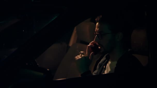 Hombre europeo habla agresivamente por teléfono y fuma cigarrillos en el coche por la noche — Vídeos de Stock