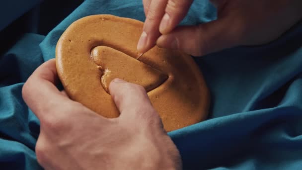 Männerhände kratzen braune Zuckerbonbons mit Metallnadelmuster in Herzform — Stockvideo