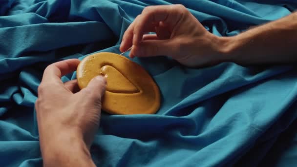 Мужские руки царапают коричневые сахарные конфеты с металлической иглой в форме сердца — стоковое видео