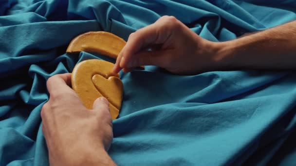 男性の手は心の形で砂糖クッキーキャンディーを破る. — ストック動画