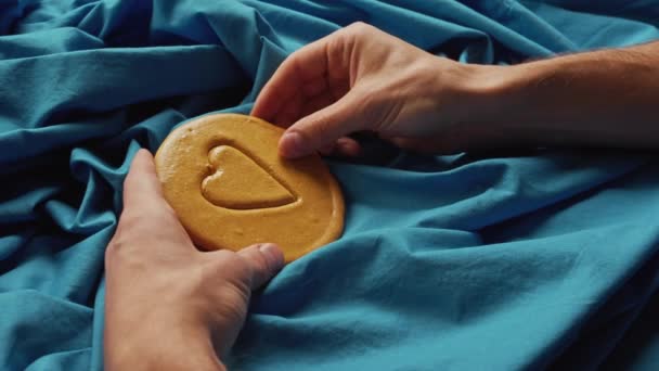 Le mani di uomini rompono la caramella di biscotti da zucchero nella forma di un cuore. — Video Stock