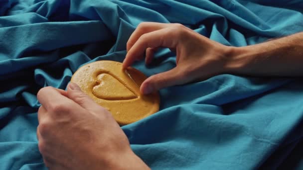 Mani degli uomini grattano zucchero biscotti caramelle a forma di cuore. — Video Stock