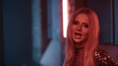 Parlak makyajlı kadın şarkıcı bir müzik videosu için stüdyoda şarkı söylüyor..