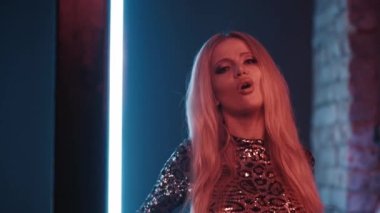 Parlak makyajlı kadın şarkıcı bir müzik videosu için stüdyoda şarkı söylüyor..