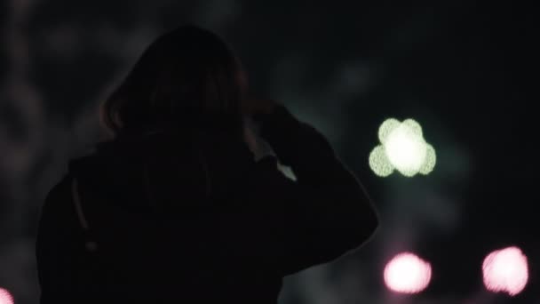 Silueta de una mujer que dispara en su smartphone fuegos artificiales multicolores — Vídeo de stock