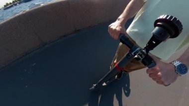 Yazın nehir boyunca elektrikli scooter kullanan bir adam.