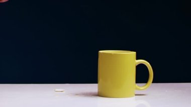 İnsan eli, sarı çay fincanını demir çekiçle kırıyor.