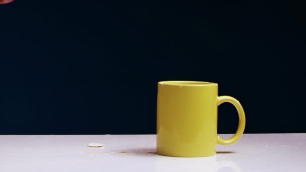 Mans hand breaks a yellow tea mug with liquid with an iron hammer — Stock Video