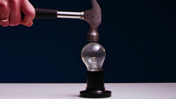 AMans mano rompe lampadina incandescente sdraiato sul tavolo con martello di ferro. — Video Stock