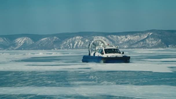 雪に覆われた山々の間の凍った湖の氷の上のホバークラフトライド — ストック動画