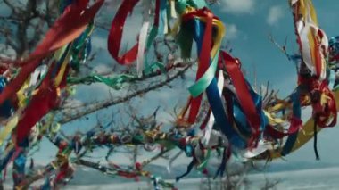 Wood with multi-colored ribbons of fabric. Religious place on Lake Baikal 