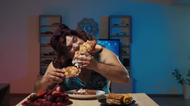 여자 옷을 입고 화장을 한 남자가 얼굴에 커다란 샌드위치를 먹는다 — 비디오