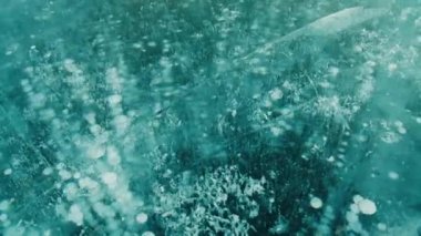 Kalın mavi donmuş su tabakası ve gölde kabarcıklar ve çatlaklar.